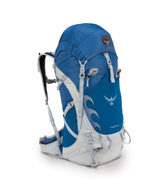 Ein kobaltblauer Rucksack mit silberweißen Gurten und Funktionen. Die Stickerei trägt die Schrift „Talon 44“ und das schwarz-rot-weiße Osprey-Logo.