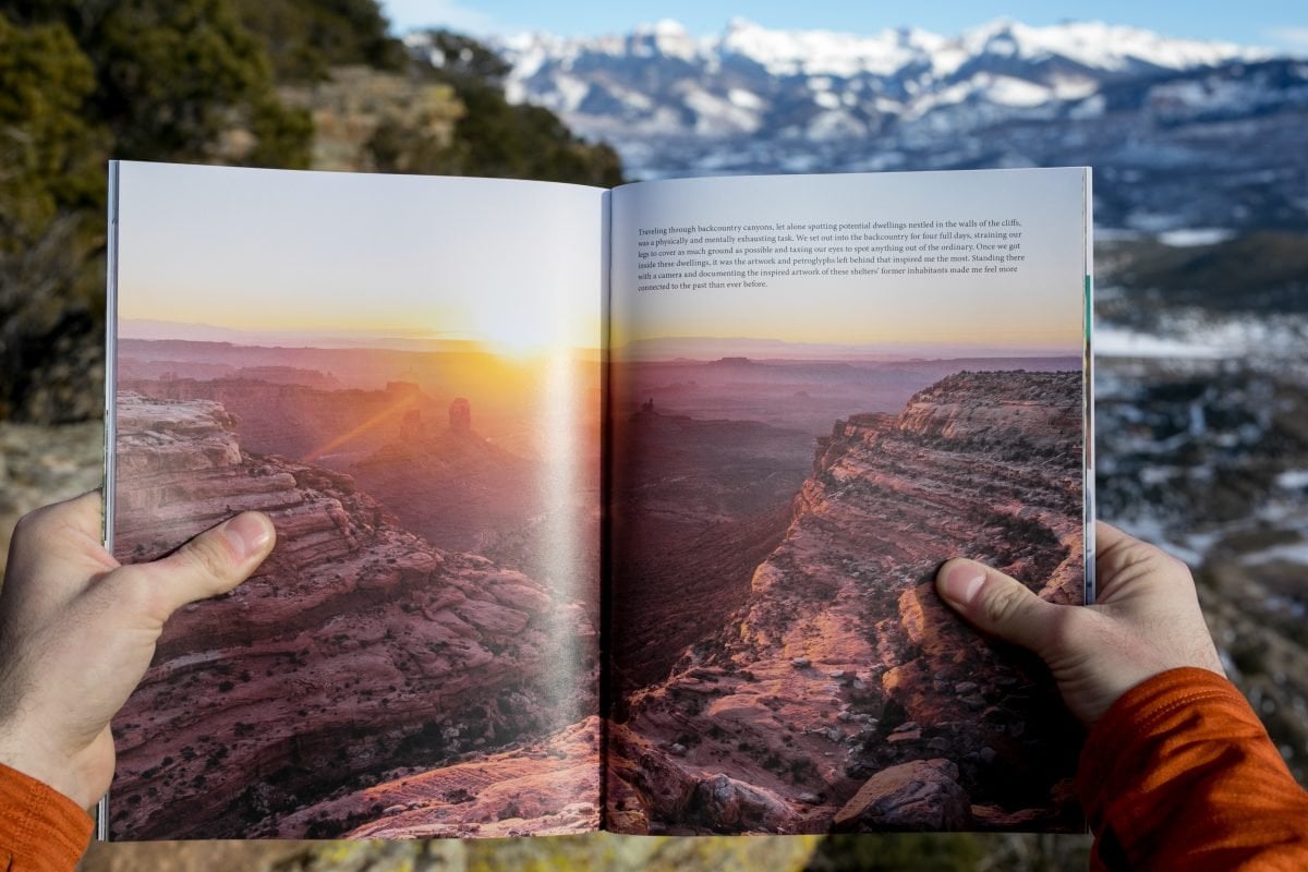 A person wearing an orange shirt holding a magazine open to a feature image with text in the top right corner