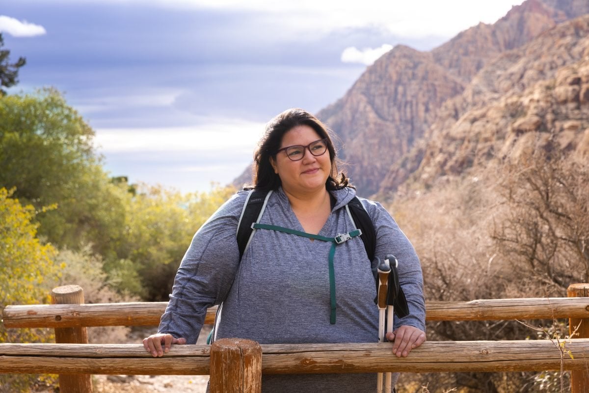 A woman smiling and looking off into the distance while standing near a wooden bridge structure