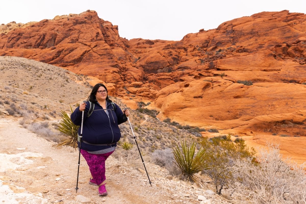 A woman wearing blue and purple hiking through the Nevada desert.