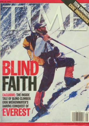 The cover of TIME magazine. Photo is of Erik Weihenmayer in a long-sleeved t-shirt, baseball cap, and expedition snow boots, standing on a steep, snow-packed slope, wearing a yellow Osprey Aether 60 and holding a hiking pole in his right hand. He is attached to a fixed line via a climbing harness, cord, and carabiner. The headline reads: &ldquo;BLIND FAITH. Exclusive: The inside tale of blind climber Erik Weihenmayer&rsquo;s daring conquest
of EVEREST.&rdquo;