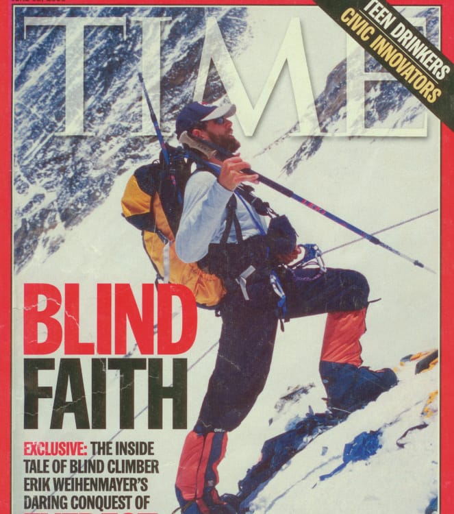 The cover of TIME magazine. Photo is of Erik Weihenmayer in a long-sleeved t-shirt, baseball cap, and expedition snow boots, standing on a steep, snow-packed slope, wearing a yellow Osprey Aether 60 and holding a hiking pole in his right hand. He is attached to a fixed line via a climbing harness, cord, and carabiner. The headline reads: &ldquo;BLIND FAITH. Exclusive: The inside tale of blind climber Erik Weihenmayer&rsquo;s daring conquest
of EVEREST.&rdquo;