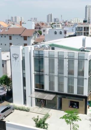 Modern office building amid a dense urban landscape, with vertical white, stainless steel and glass panels. A stainless steel Osprey logo is on the main fa&ccedil;ade on the left. Green plants are growing in planters on the side of the building.