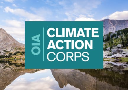 The teal and white OIA Climate Action Corps logo over a photo of a granite and forested mountain area with a glassy, reflective alpine lake and a blue sky.
